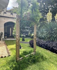 a mirror sitting in the middle of a lush green field next to a building and trees