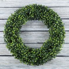 a boxwood wreath hanging on a wooden wall