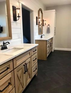 a large bathroom with two sinks, mirrors and lights on the wall above them is shown