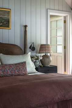 a bed sitting in a bedroom next to a lamp on top of a wooden headboard