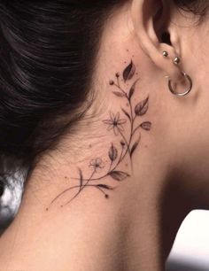 a woman's neck with a flower tattoo on her left side behind the ear