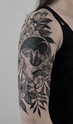 a woman's arm with flowers and an animal in the middle, on top of it