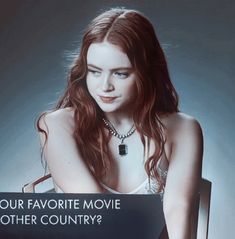 a woman sitting in a chair holding a sign that says your favorite movie is another country?