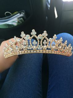 a woman wearing a tiara sitting in the back seat of a car with her legs crossed