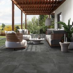 an outdoor living area with wicker furniture and stone flooring is shown in this image