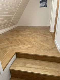 an empty room with wood floors and white walls, next to a staircase that leads up to the second floor