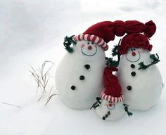 three snowmen wearing red hats and scarfs in the snow