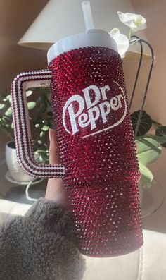 a person holding up a red and white cup with the word dr pepper on it