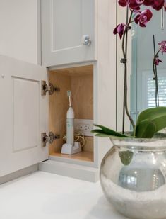 a vase filled with pink flowers sitting on top of a counter next to a mirror