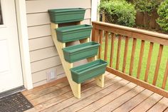 three green planters sitting on the side of a wooden deck next to a door