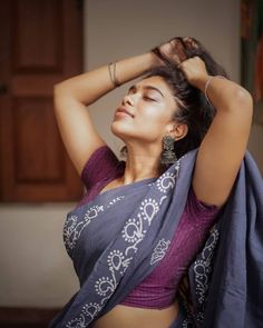 a woman in a sari is holding her hair up and posing for the camera