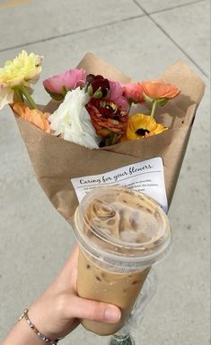 a person holding up a cup of coffee with flowers in the wrapper on it