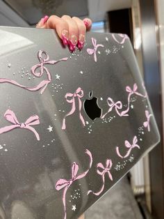 a woman holding an apple computer with pink bows on it's side and the bottom part of her body