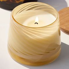 a white candle sitting on top of a table next to a wooden bowl and plate