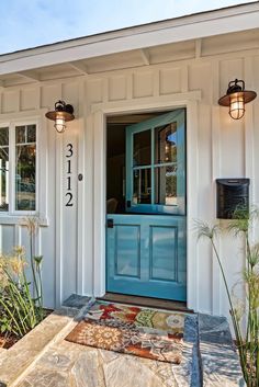 the front door of a house with two lights on it and a rug in front