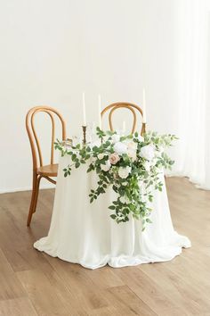 the table is set with white flowers and greenery for an elegant wedding centerpiece