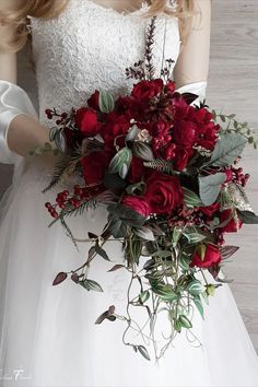 a bride holding a bouquet of red flowers