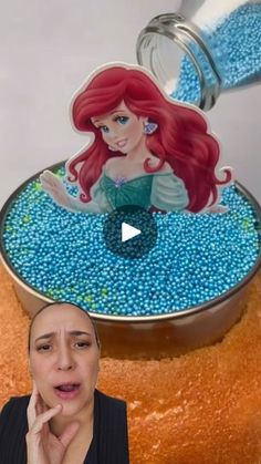 a woman standing in front of a cake that has been made to look like ariel from the little mermaid