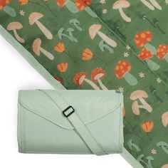 a green bag with mushrooms on it next to a large piece of fabric that has been folded over