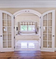 an open door leading to a bathroom with a tub in the corner and wooden floors