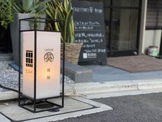 a lit up lantern sitting on the side of a road next to a planter filled with succulents