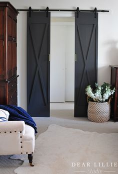 a living room with two sliding doors and a white chair in front of the couch