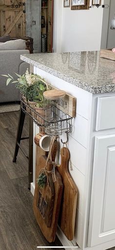 a kitchen with white cabinets and wooden cutting boards hanging on the wall next to an island