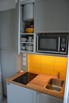 a kitchen with white cabinets and yellow tile backsplash, stainless steel sink and microwave