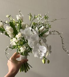 a person holding a bouquet of white flowers in their left hand and the other hand is reaching for it