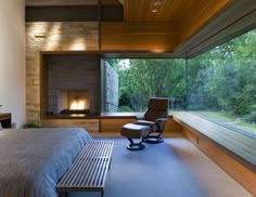 a bedroom with a bed, chair and fireplace in the corner next to window overlooking trees