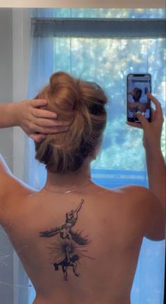 a woman with a tattoo on her back taking a selfie