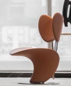 an orange chair sitting in front of a window next to a black and white clock