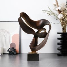 a sculpture sitting on top of a table next to a vase with flowers in it