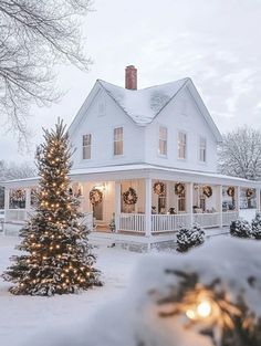 a large white house covered in snow with christmas lights on the front porch and trees