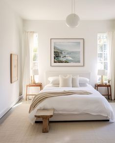 a large white bed sitting in a bedroom next to two tables with lamps on them