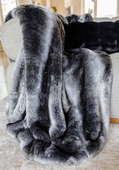 a large grey fur rug sitting on top of a white table next to a couch