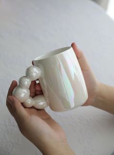 a person holding a coffee cup with pearls on it