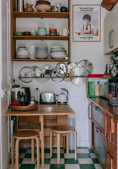 a kitchen with green and white checkered flooring next to shelves filled with pots and pans