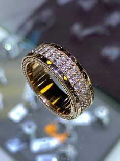 a gold ring with white and yellow diamonds on it's side, sitting on a table