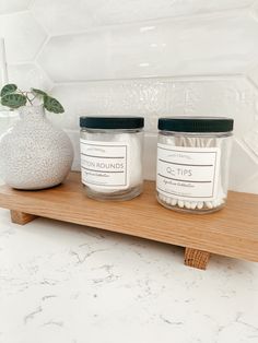 two jars are sitting on a shelf next to a potted plant