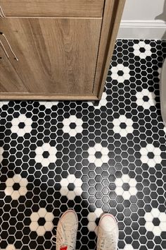 a person standing on a black and white tiled floor in front of a wooden cabinet