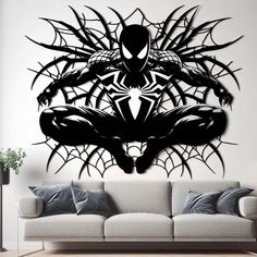 a living room with a white couch and black spiderman wall decal