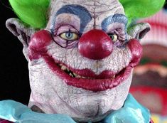 a close up of a clown's face with green hair