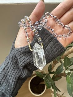 This stunning Clear Quartz Crystal Necklace is the perfect blend of elegance and spiritual energy. Featuring a striking, raw clear quartz point pendant, this necklace is hand-strung with clear quartz beads and gold-tone accents, adding a radiant touch to any outfit. The necklace is both a statement piece and a tool for spiritual healing, designed to amplify positive energies and promote mental clarity. Product Details: *Crystal: Natural Clear Quartz Point *Pendant Size: Approx. 5cm *Chain: Clear Quartz Beads with Gold-tone Spacer Beads *Chain Length: 21cm *Handmade with Love Properties of Clear Quartz: Clear Quartz is known as the "Master Healer," amplifying energy, thoughts, and the effects of other crystals. It is a highly prized stone for those looking to enhance their focus, clarity, a Spiritual Round Beads Crystal Necklaces For Layering, Spiritual Crystal Necklaces With Round Beads For Layering, Healing Faceted Crystal Necklaces, Adjustable Quartz Crystal Necklace Spiritual, Adjustable Quartz Crystal Spiritual Necklace, Spiritual Quartz Crystal Necklace, Spiritual Faceted Beads Crystals As Gift, Spiritual Crystal Beaded Necklaces As Gift, Spiritual Crystal Beaded Necklaces For Gifts