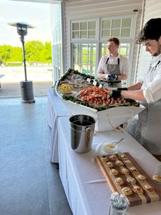 two people preparing food on a long table