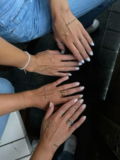 four women's hands are stacked on top of each other with their fingers together