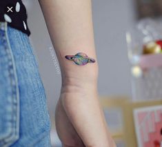 a woman's arm with a small tattoo on the wrist and an object in the background