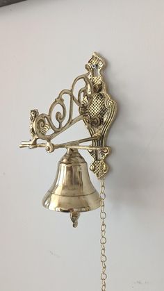 a bell hanging from the side of a wall next to a chain attached to it