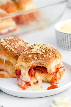 two sandwiches with cheese and tomato sauce on a white plate next to other food items