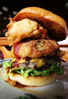 a hand holding a chicken sandwich with bacon, lettuce and cheese on it